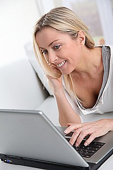 Adult blond woman connected on internet at home