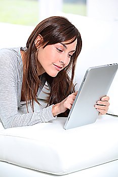 Young woman sitting on sofa with electronic pad