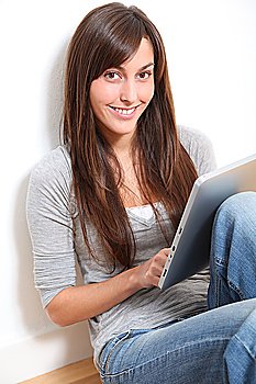 Young woman sitting on the floor with electronic pad