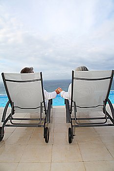 Senior couple relaxing in long chairs