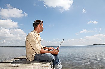 Man using laptop computer on a pontoon