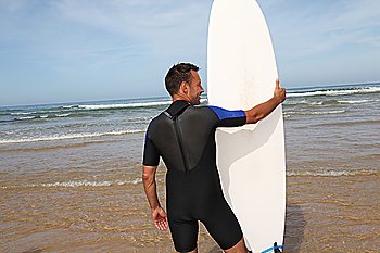 Man standing in water with surfboard