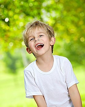 Portrait of the laughing loudly boy against a summer garden