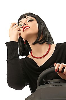 The girl puts lipstick being at the wheel an autosimulator, isolated