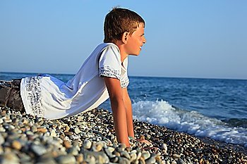 teenager boy lying on stones on seacoast