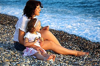 Mother with daughter sits on seacoast
