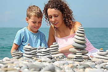 mother and son builds  stone stacks on pebble beach