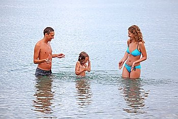 Happy family with little girl splashes water hands standing on belt in sea, Sprinkle daughter