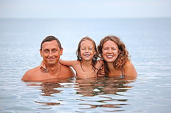 Happy family with little girl bathe in sea