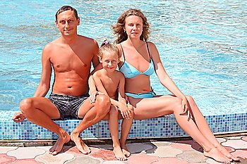 Happy family with little girl sit near in pool