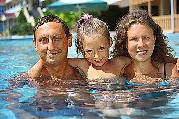 happy smiling family with little girl in pool hugging
