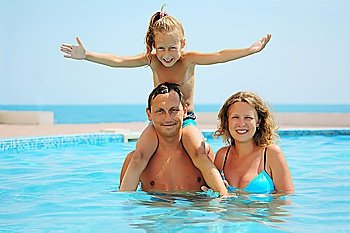 smiling family in pool. Daughter sits on fathers shoulder