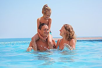 happy family in pool on sea background. Daughter sits on fathers shoulders