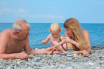 Mother and grandfather with child on sea coast and  pyramid of stones