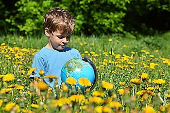 boy with globe on meadow among blossoming dandelions