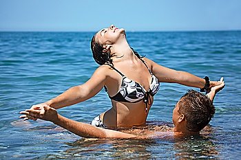 young hot woman sitting astride man in sea near coast, Having joined hands