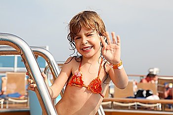caucasian little girl standing on cruise ship, smiling and waving hand focus on face