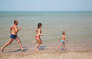 Grandfather with daughter and grandson run as to beach 