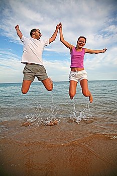 Man and woman jump above the sea
