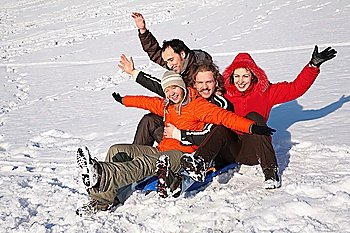 group of friends sit on plastic sled on snow