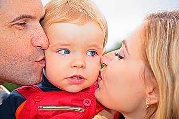 Parents kiss child outdoors