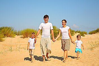 Family of four walk on sand