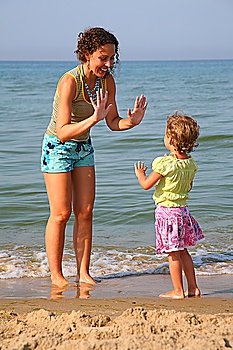 Mother plays with daughter on beach, okee-dokee