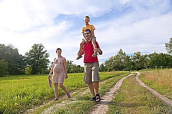 Happy family with pregnant woman, kid and father walking on the road