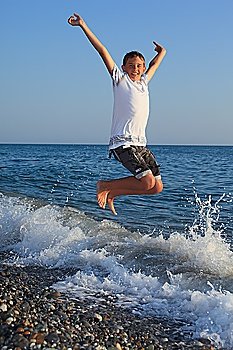 jumping teenager boy on stone seacoast