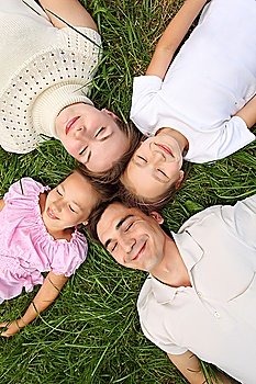 Parents with children lying on grass, view from top, head to head