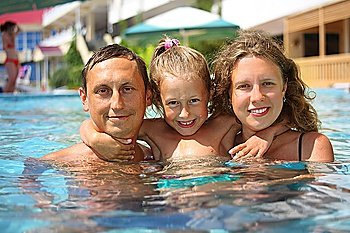 happy family with little girl in water hugging