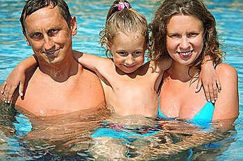 happy smiling family with little girl in water hugging