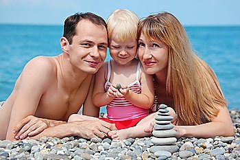 Parents with child on sea coast and  pyramid of stones