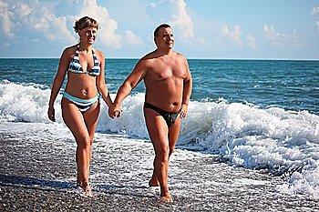 middleaged pair walk on pebble beach