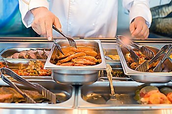 hand of cook takes nippers fried meat in lunch counter at public catering restaurant