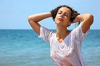 beautiful woman in wet clothes on seacoast, closed eyes