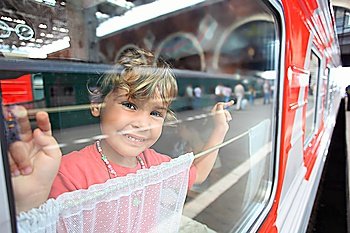 Smiling little girl look from train window