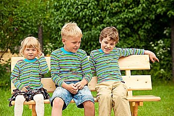Three children on a bench in identical clothes