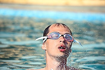 young man in watersport goggles swimming in pool, Aome up from water, taking breath