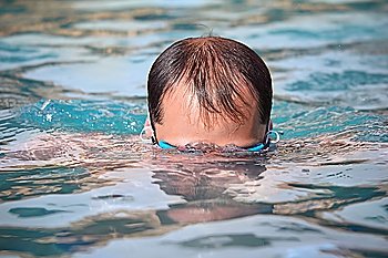 young man in watersport goggles swimming in pool, dives under water
