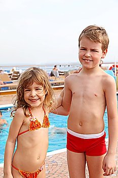 caucasian little girl and boy standing on cruise ship and smiling