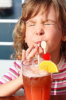 little girl in shirt with pink stripes drinking cocktail with fruits, eyes closed