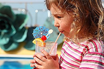 little girl in shirt with pink stripes drinking cocktail with fruits, side view