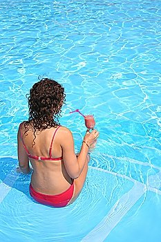 The woman with a drink sits in pool
