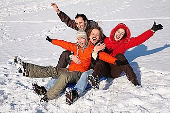 group of friends sit on plastic sled on snow 2