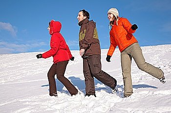 three friends walk on snow on hillside