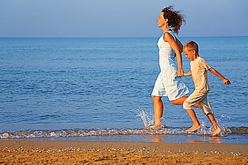 Mother with son running on edge of sea
