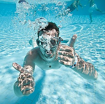 man floats underwater in pool