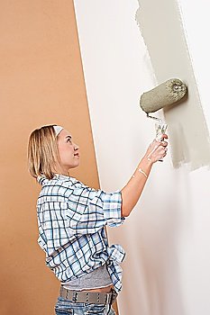 Home improvement: Blond woman painting wall with paint roller