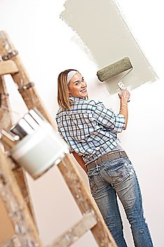 Home improvement: Blond woman painting wall with paint roller
